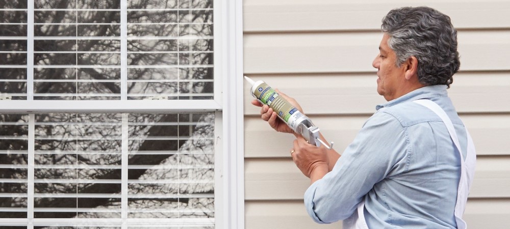 A homeowner applies metallic silicone sealant to a metal surface in a home