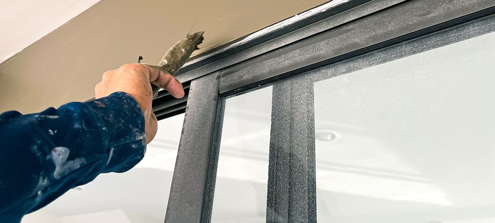 A homeowner painting acrylic over caulk.